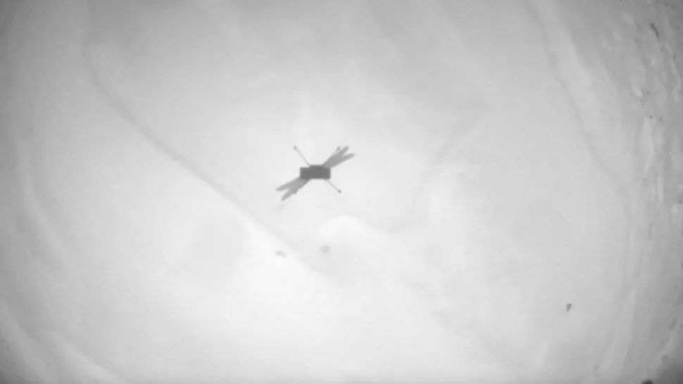 op een zwart-witfoto is een schaduw van een kleine drone te zien op zandgrond.