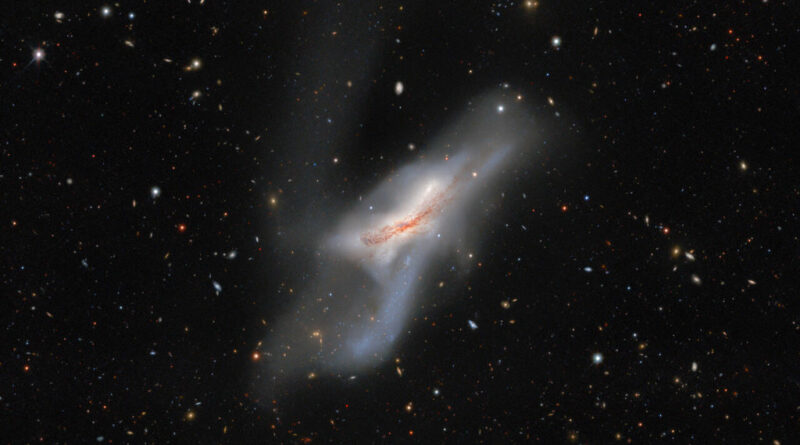 Tegen de achtergrond van de ruimte is een piekerig wit sterrenstelsel te zien. In de ruimte vertegenwoordigen een aantal andere heldere stippen en lijnen sterrenstelsels en objecten in het universum, die per ongeluk in deze afbeelding zijn vastgelegd.