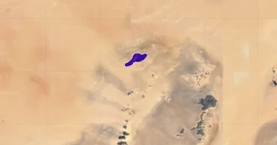 Een luchtfoto van een zandkleurig gebied. Een donkerpaarse vlek vertegenwoordigt de gedetecteerde EMIT-bron van de methaanpluim.