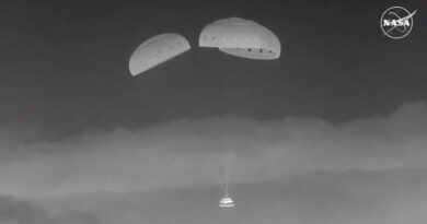 zwart-witfoto van een ruimtecapsule die onder drie parachutes door de nachthemel daalt